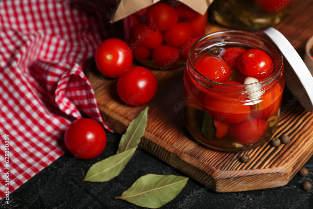 Jars with canned tomatoes and peppercorn on black background