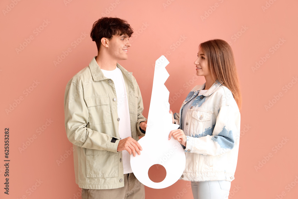 Young couple with paper key on color background