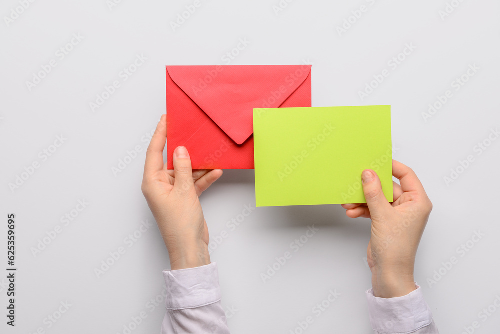 Female hands with envelope and blank card on white background