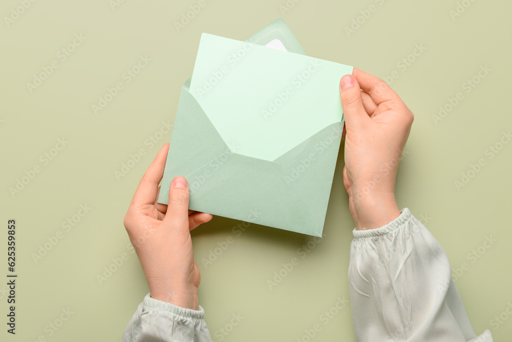 Female hands with paper envelope and blank card on color background, closeup