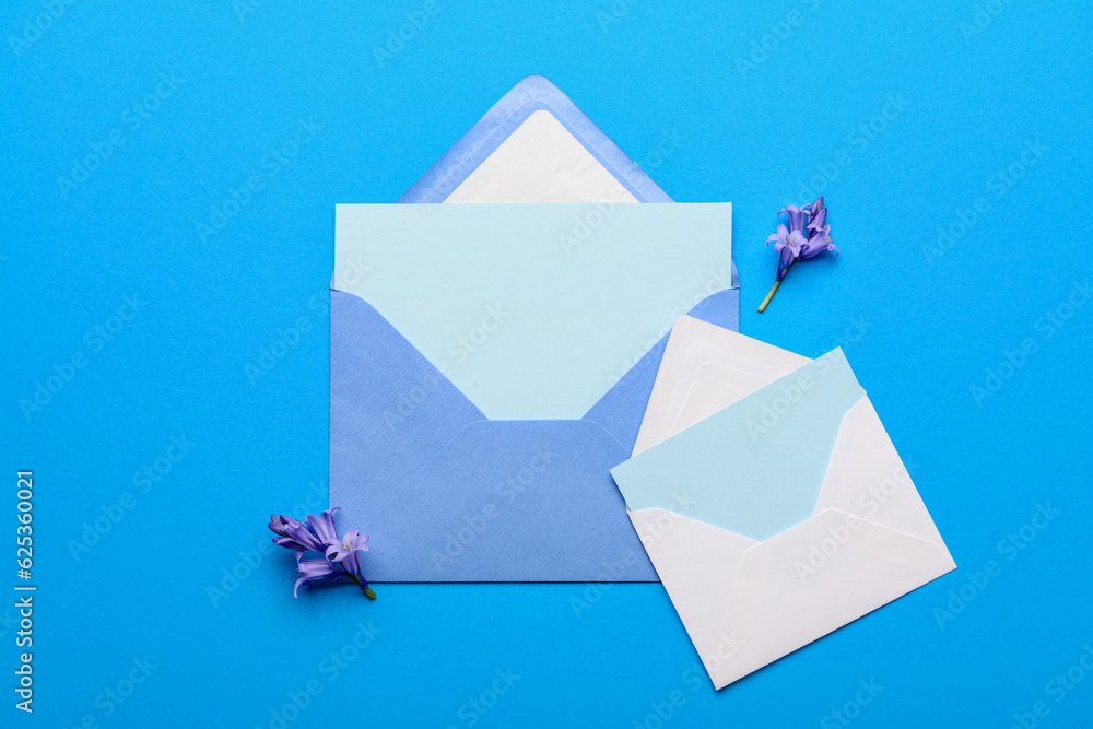 Paper envelopes with blank cards and flowers on color background