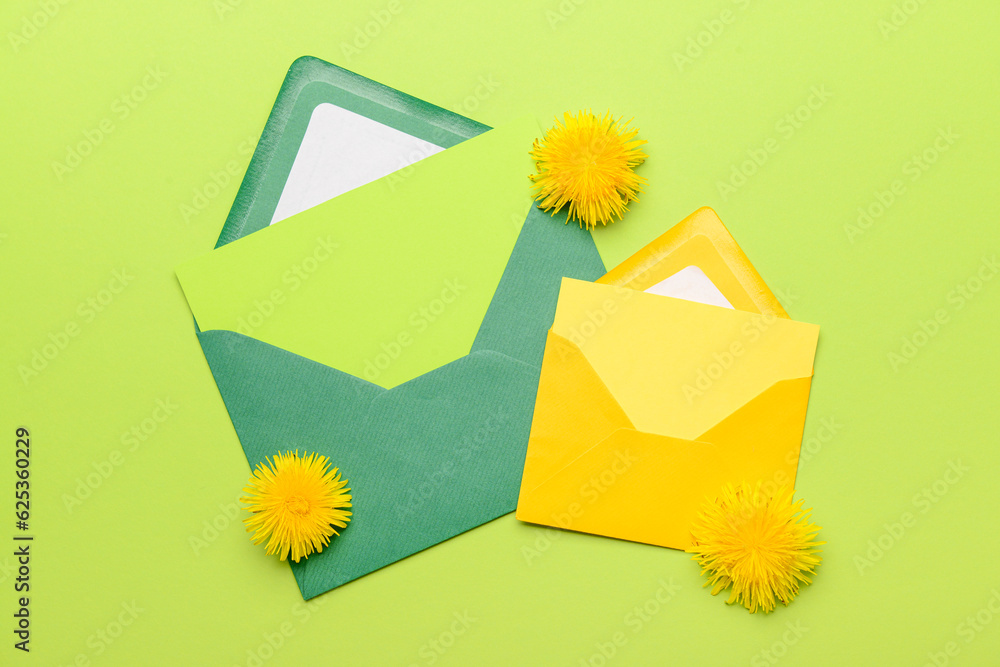 Paper envelopes with blank cards and dandelions on green background