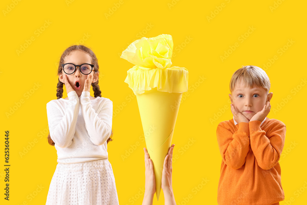 Mother greeting her surprised children with school cone on yellow background