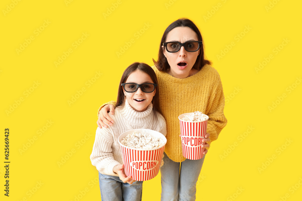 Little girl and her mother in 3D glasses with popcorn on yellow background