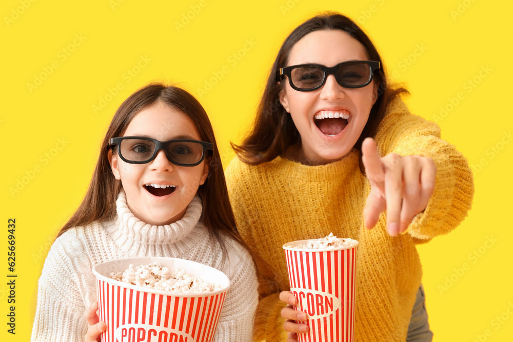 Little girl and her mother in 3D glasses with popcorn on yellow background