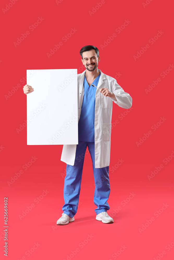 Male dentist with brush and big plastic tooth on red background