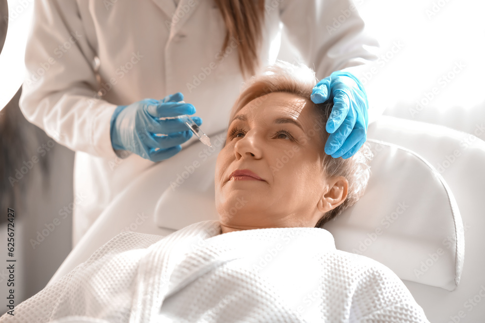 Mature woman receiving filler injection in beauty salon, closeup