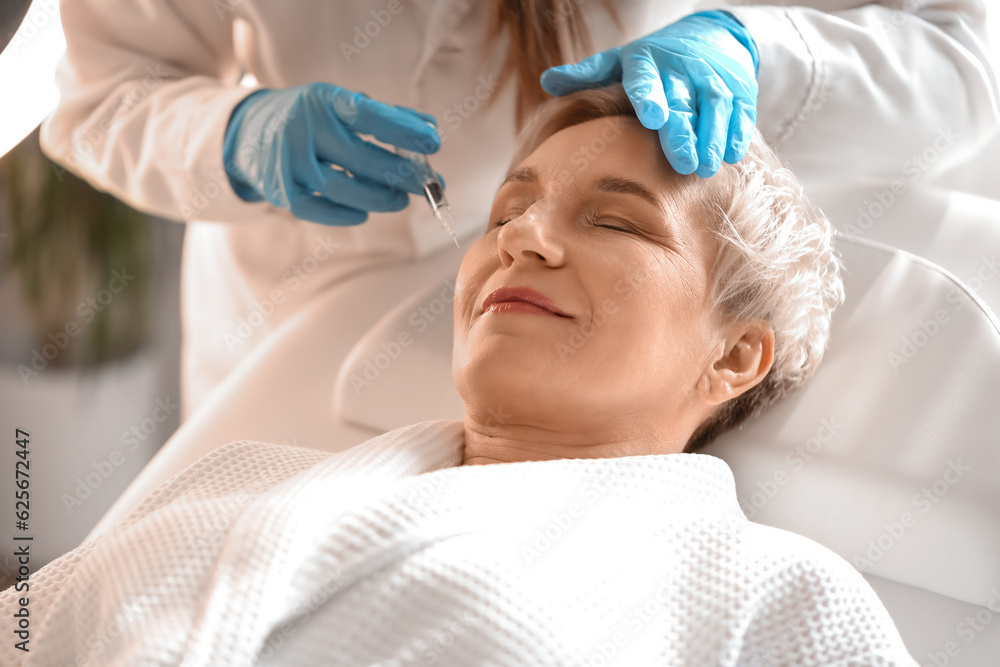 Mature woman receiving filler injection in beauty salon, closeup