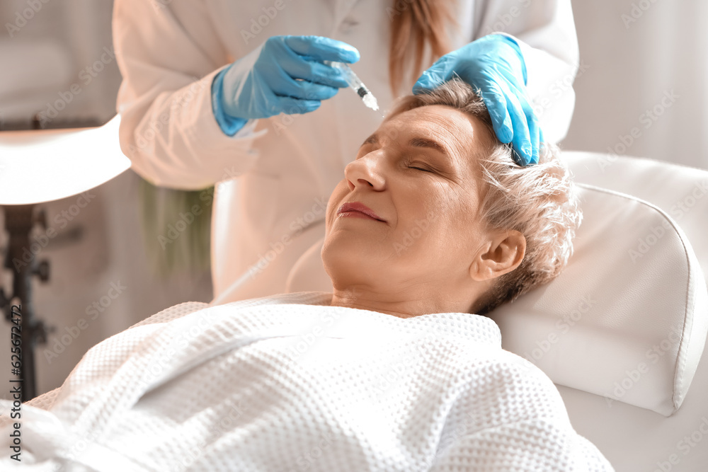 Mature woman receiving filler injection in beauty salon, closeup