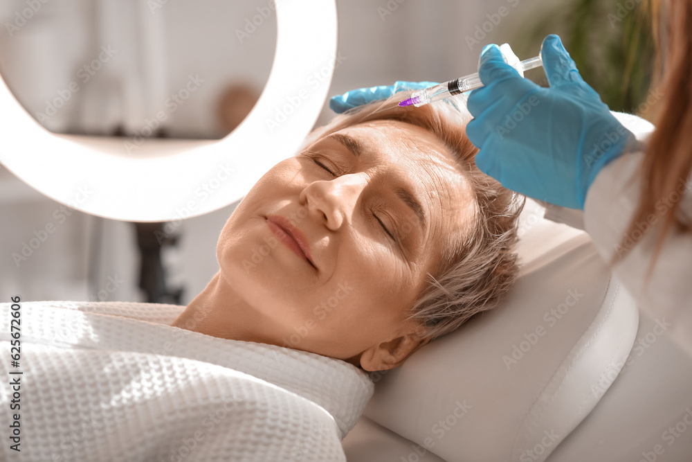 Mature woman receiving filler injection in beauty salon, closeup