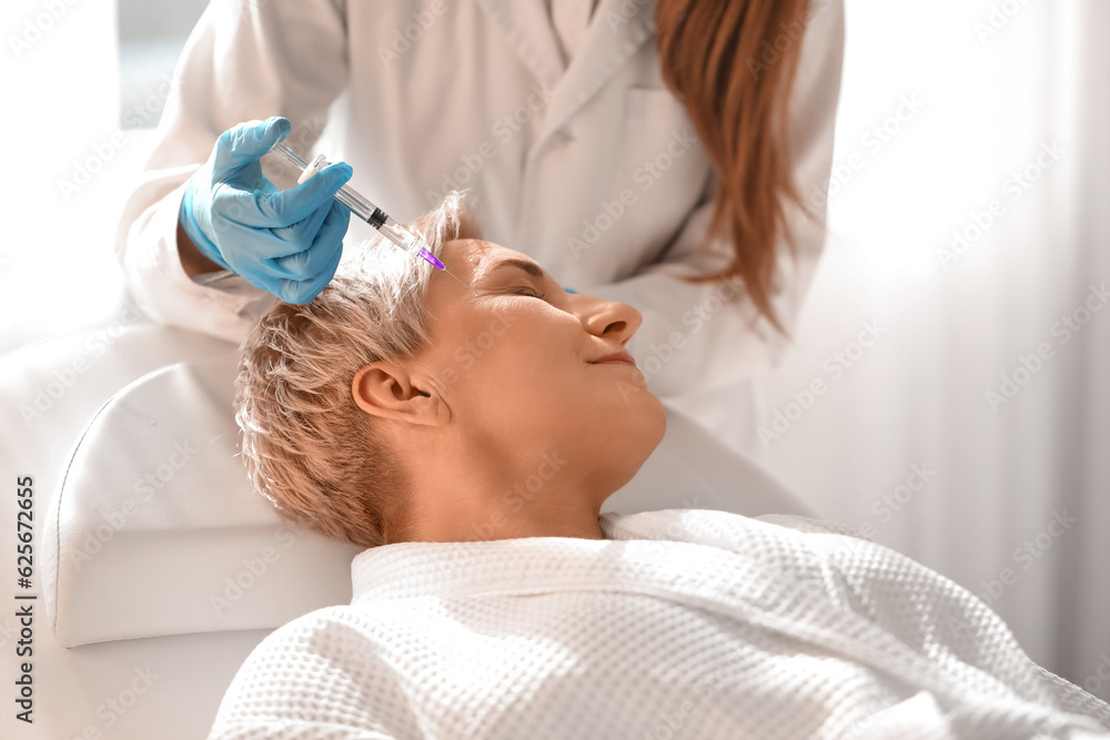 Mature woman receiving filler injection in beauty salon, closeup