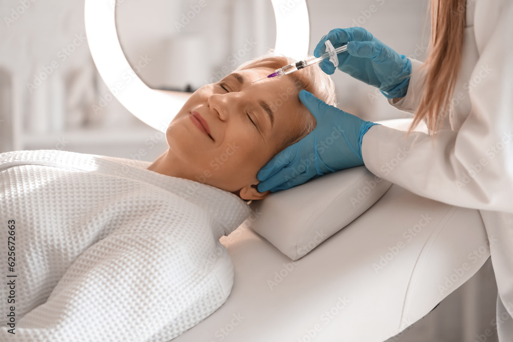 Mature woman receiving filler injection in beauty salon, closeup