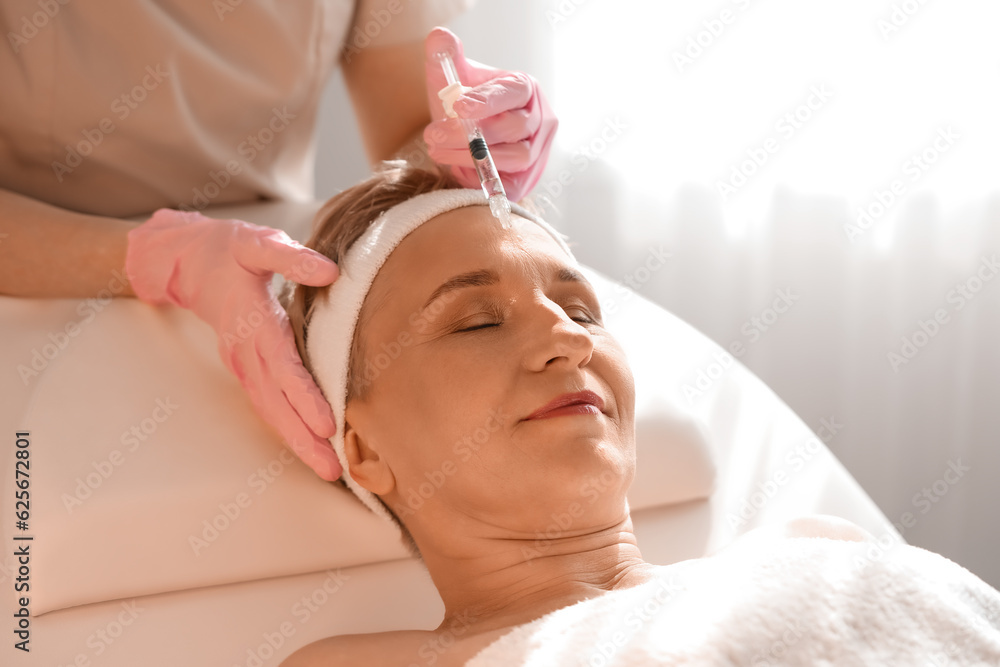 Mature woman receiving filler injection in beauty salon, closeup