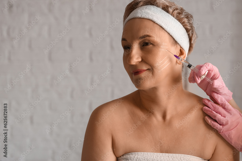 Mature woman receiving filler injection in beauty salon, closeup