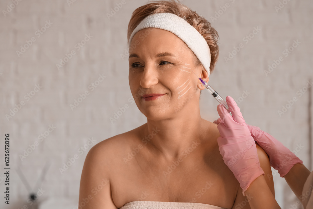 Mature woman receiving filler injection in beauty salon, closeup