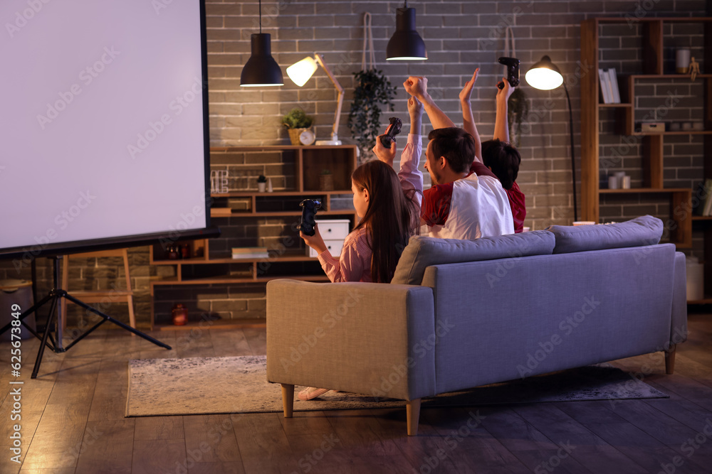 Father with his little children playing video game at home in evening