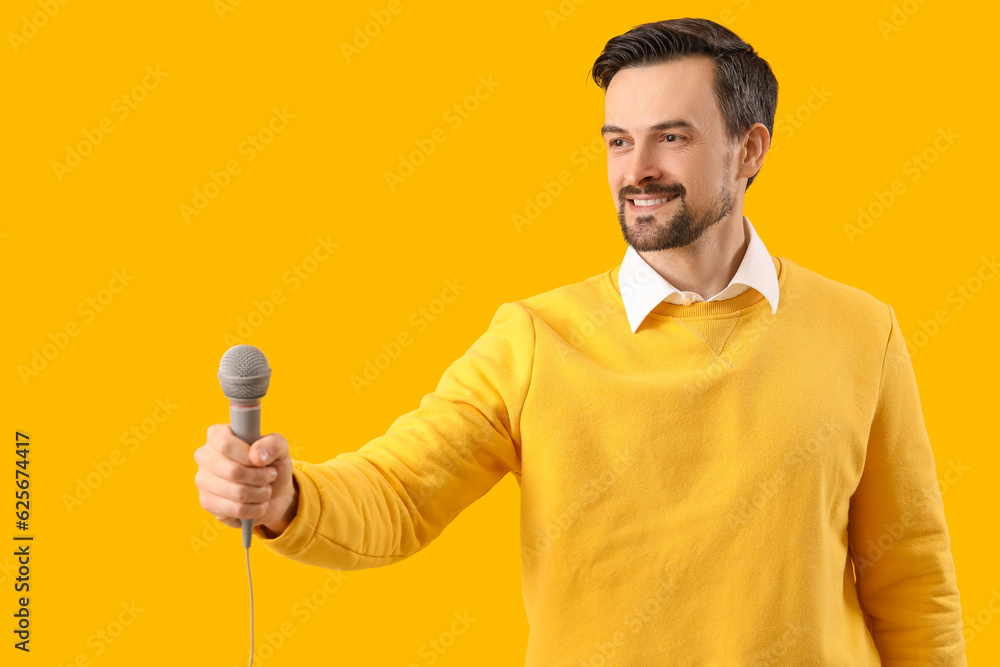 Male journalist with microphone on yellow background