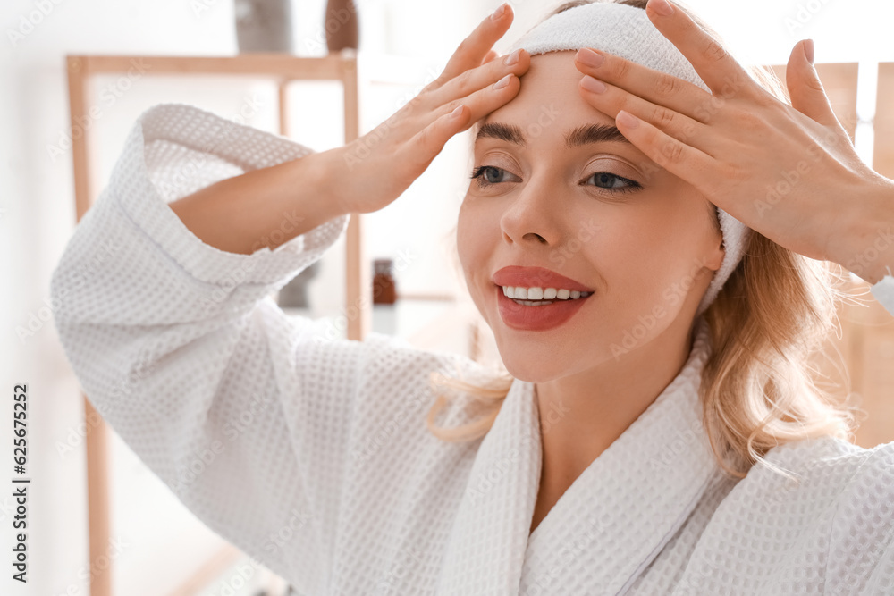 Young woman doing face building exercise in bathroom, closeup