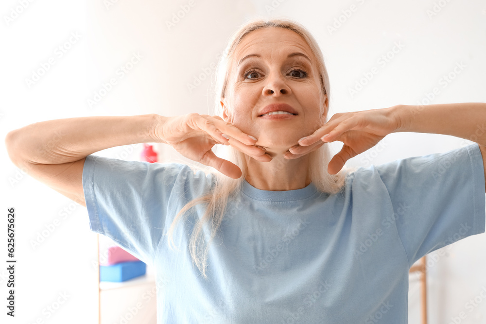 Mature physiotherapist doing face building exercise in rehabilitation center