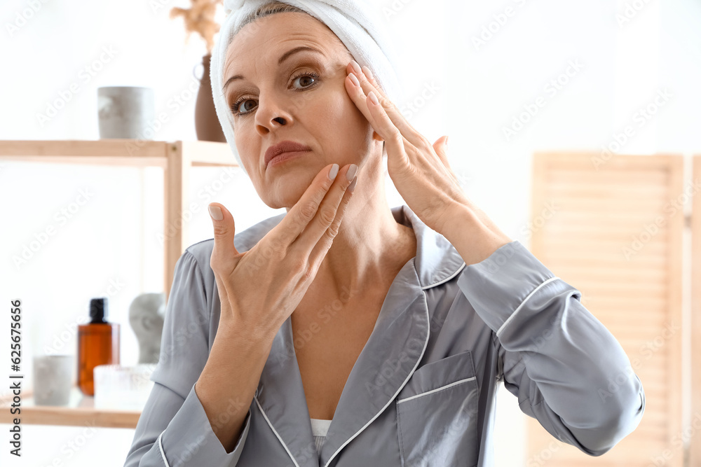 Mature woman doing face building exercise in bathroom