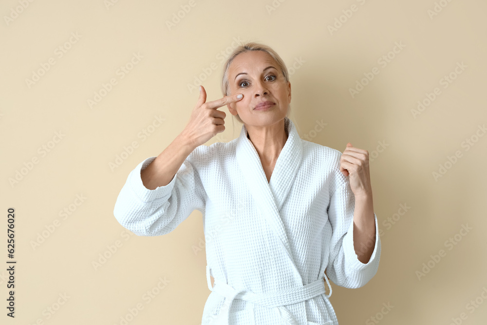 Mature woman doing face building exercise on beige background