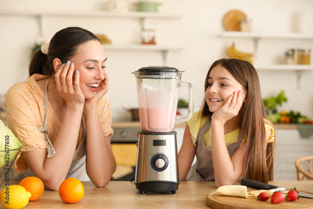 Little girl and her mother making smoothie with blender in kitchen