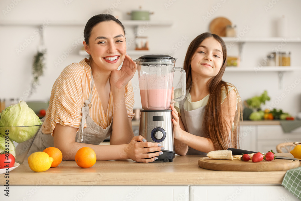 Little girl and her mother making smoothie with blender in kitchen