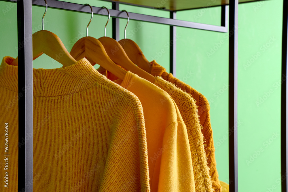 Stylish clothes hanging near green wall, closeup