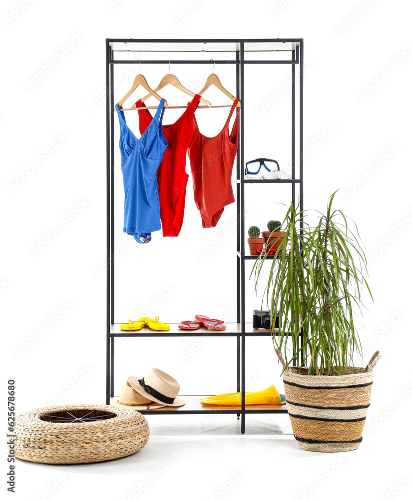 Shelving unit with beach accessories, palm tree and pouf on white background