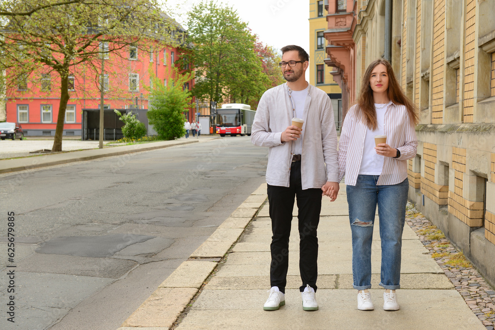 Beautiful loving happy couple drinking coffee and walking in city on spring day