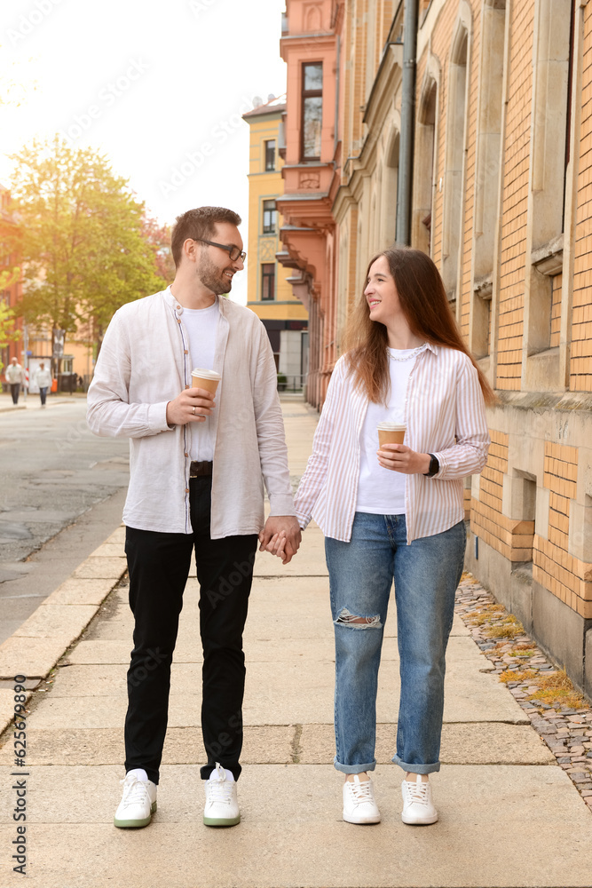 Beautiful loving happy couple drinking coffee and walking in city on spring day