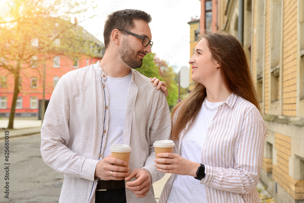 Beautiful loving happy couple drinking coffee and walking in city on spring day