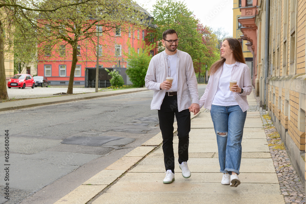 Beautiful loving happy couple drinking coffee and walking in city on spring day