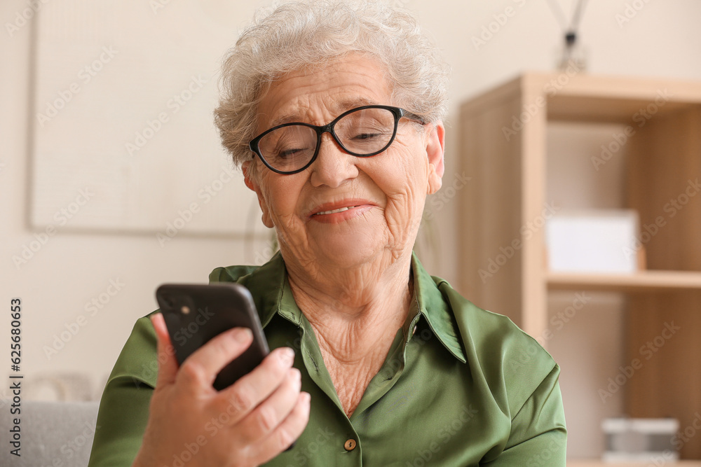 Senior woman using mobile phone at home, closeup