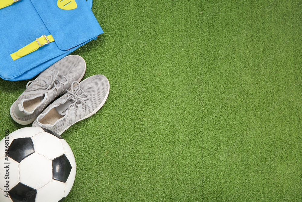 Sneakers with backpack and soccer ball on color background