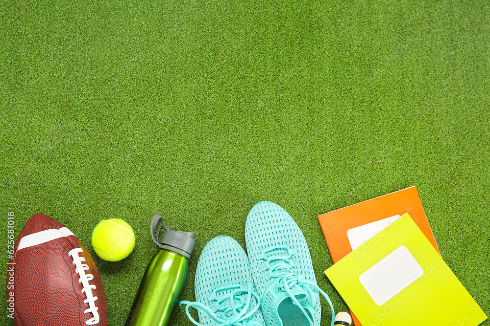 Sneakers with sport balls, bottle of water and notebooks on color background