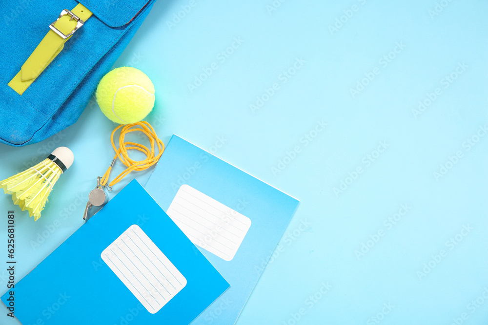 Backpack with tennis ball, whistle, badminton shuttlecock and notebooks on blue background