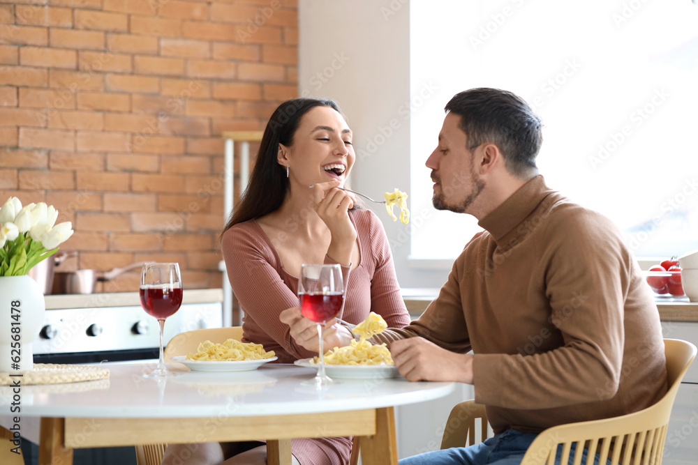 Happy young couple having dinner in kitchen