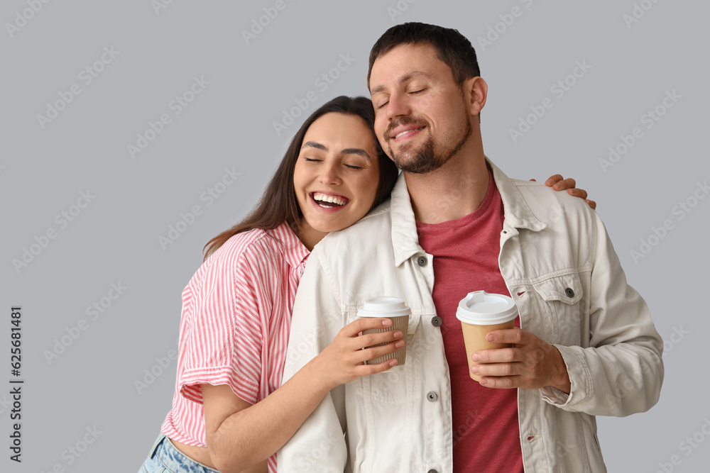 Happy young couple with cups of coffee on light background