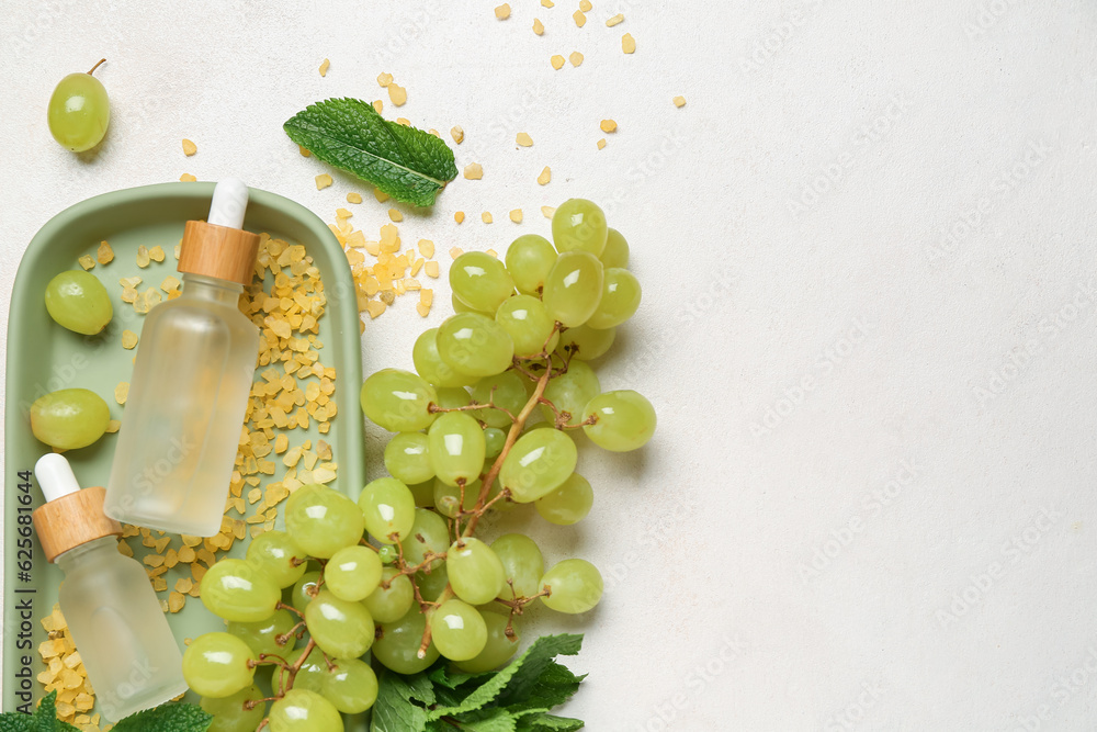 Bottles with cosmetic oil, sea salt and grapes on white background