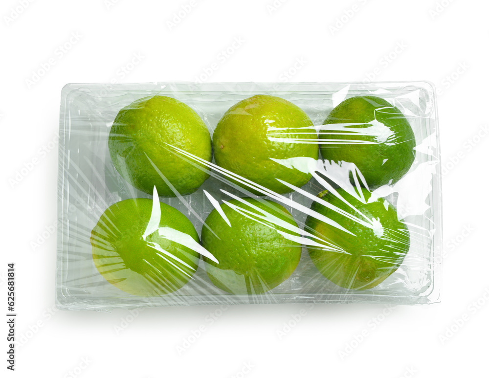 Fresh limes in plastic food wrap on white background