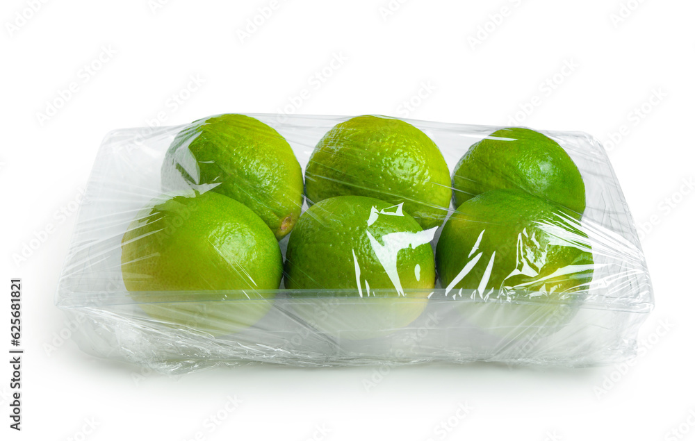 Fresh limes in plastic food wrap on white background