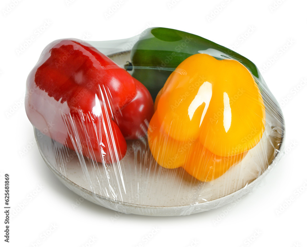 Plastic food wrap with sweet peppers on white background