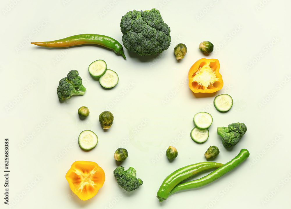 Frame made of different fresh vegetables on green background