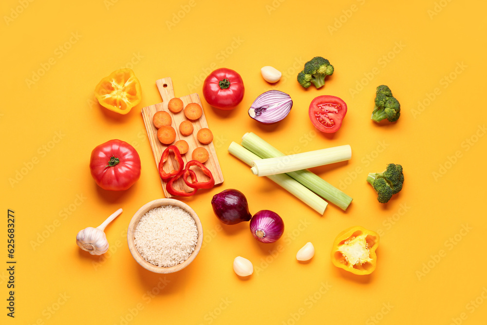 Bowl with rice and different fresh vegetables on orange background