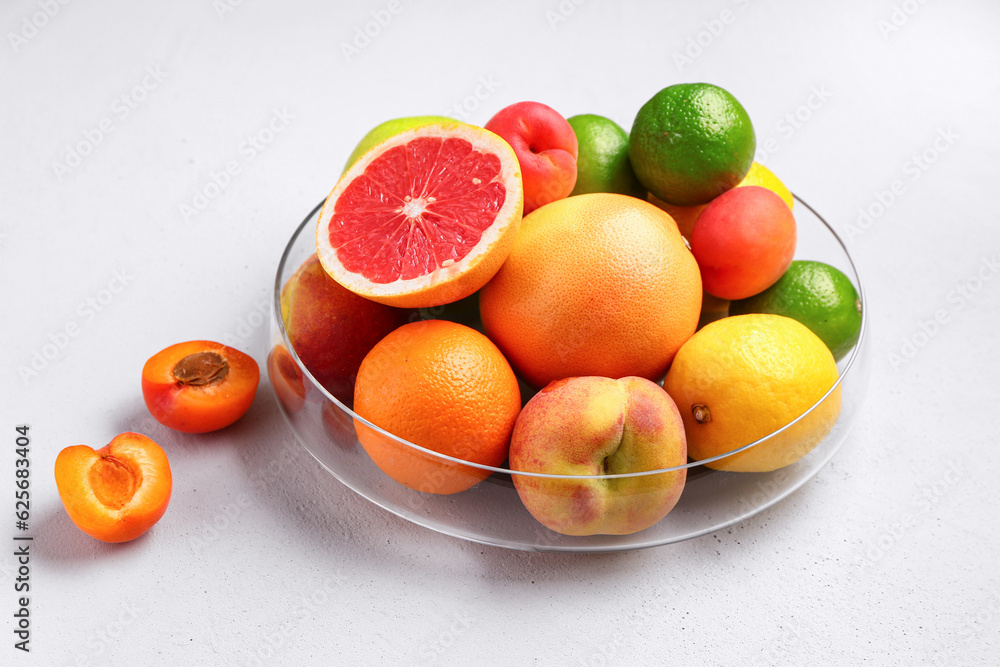 Bowl with different fresh fruits on grey background