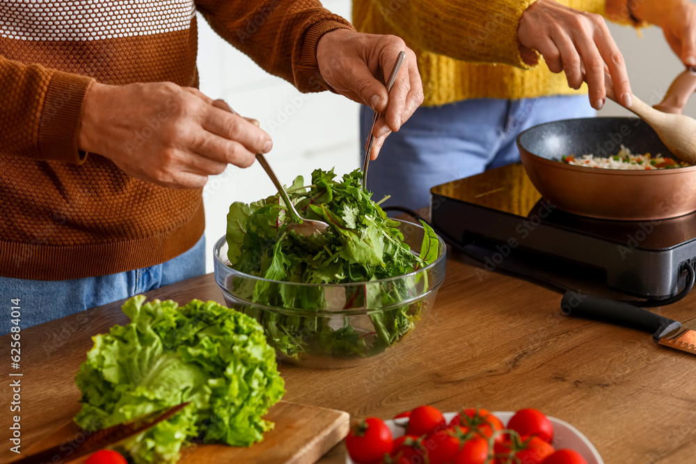 Mature couple cooking in kitchen, closeup