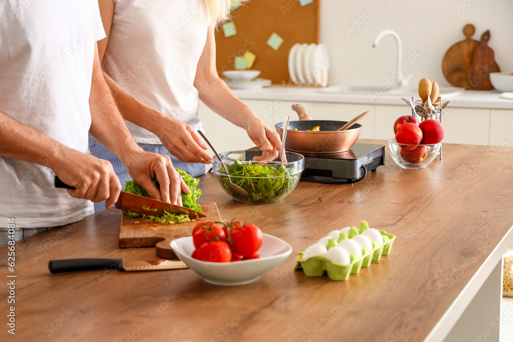 Mature couple cooking in kitchen, closeup