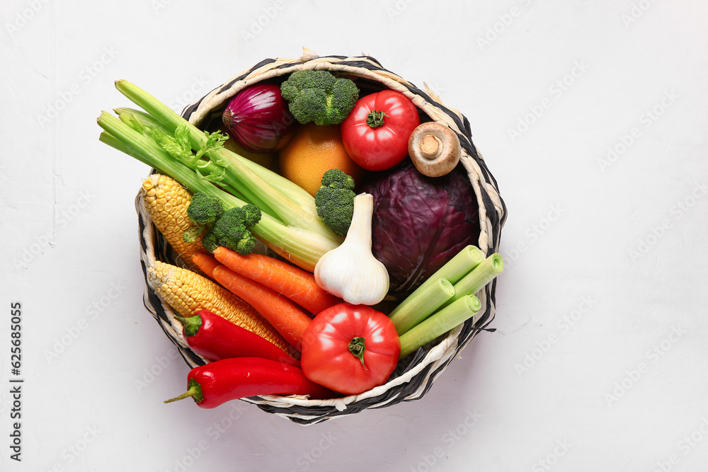 Wicker bowl with different fresh vegetables on white background