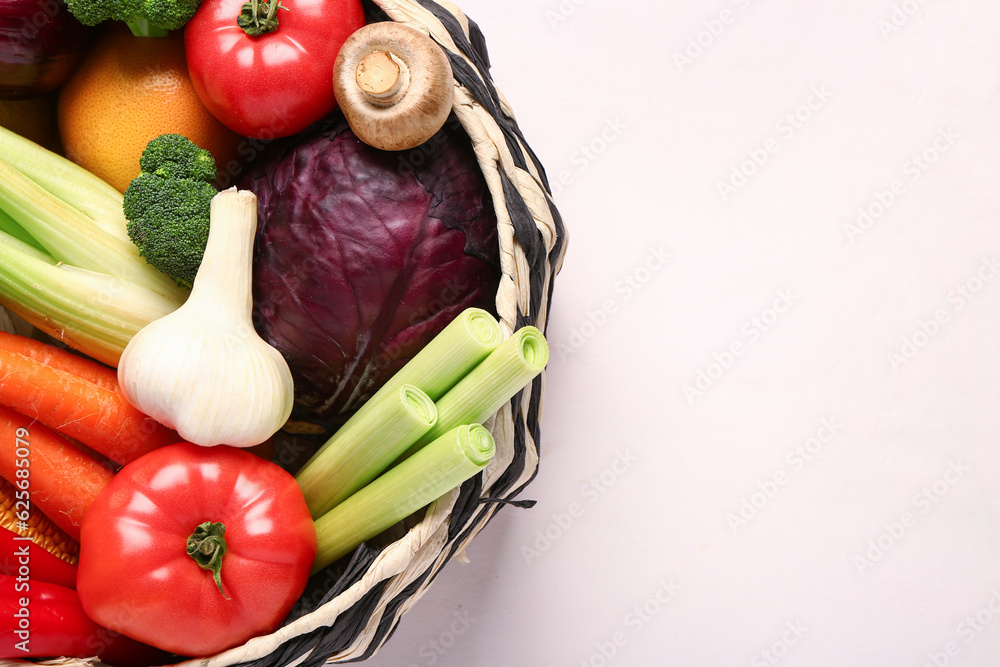 Wicker bowl with different fresh vegetables on white background, closeup